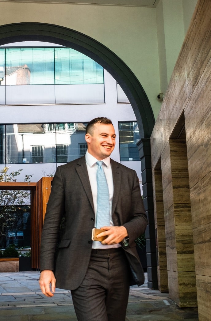 Man in suit smiling as he walks through an archway.