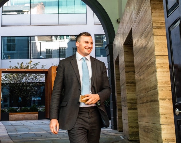 Man in suit smiling as he walks through an archway.
